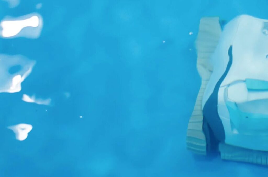 Robot pool cleaner operating at night in a residential backyard