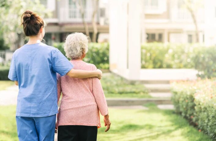 Nurse and resident looking at a garden maintained by a robot mower